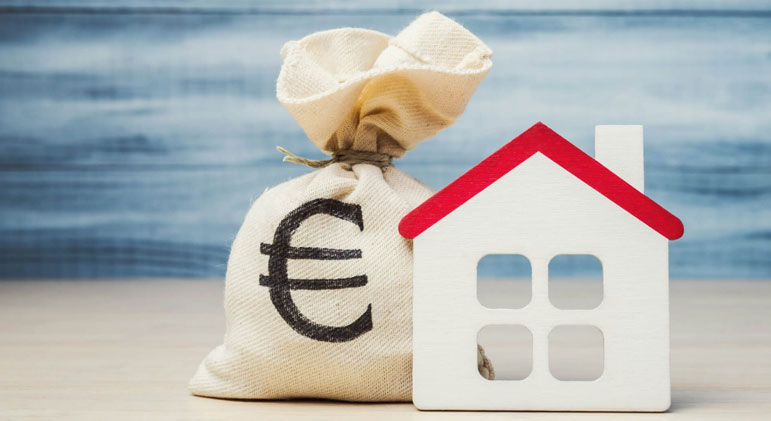 Un sac d'argent avec le symbole de l’euro à côté d’une maison miniature en bois, représentant l’investissement immobilier et les finances liées au logement.