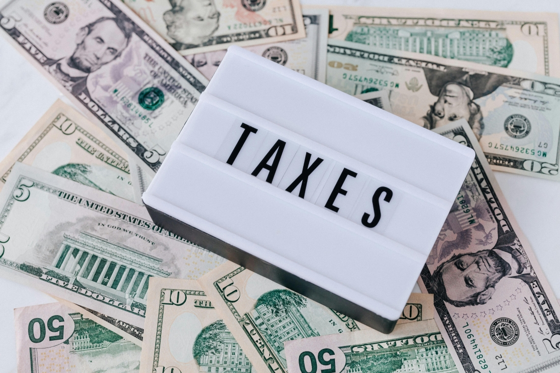 Ensemble de billets de banque américains entourant une boîte lumineuse affichant le mot "TAXES".