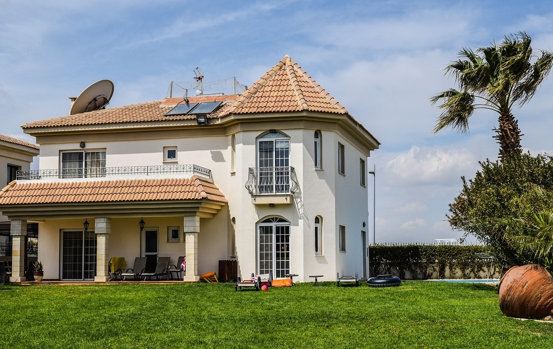 Grande résidence secondaire moderne avec toit en tuiles et jardin arboré.