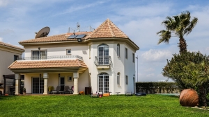 Grande résidence secondaire moderne avec toit en tuiles et jardin arboré.