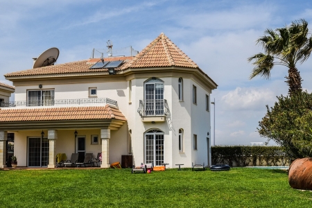 Grande résidence secondaire moderne avec toit en tuiles et jardin arboré.