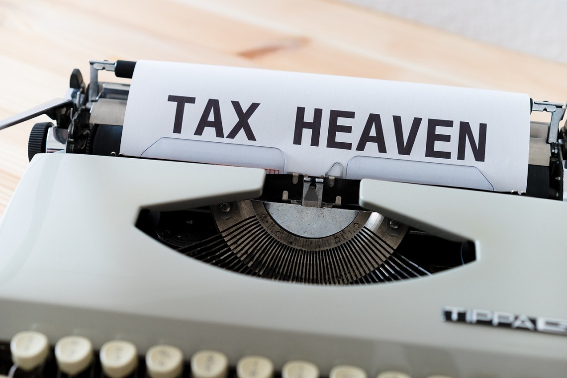 Feuille avec les mots "TAX HEAVEN" insérée dans une machine à écrire vintage.
