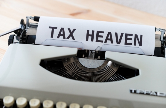 Feuille avec les mots "TAX HEAVEN" insérée dans une machine à écrire vintage.